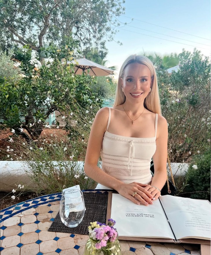 Elena Persson sitting at a table in a garden and smiling at the camera